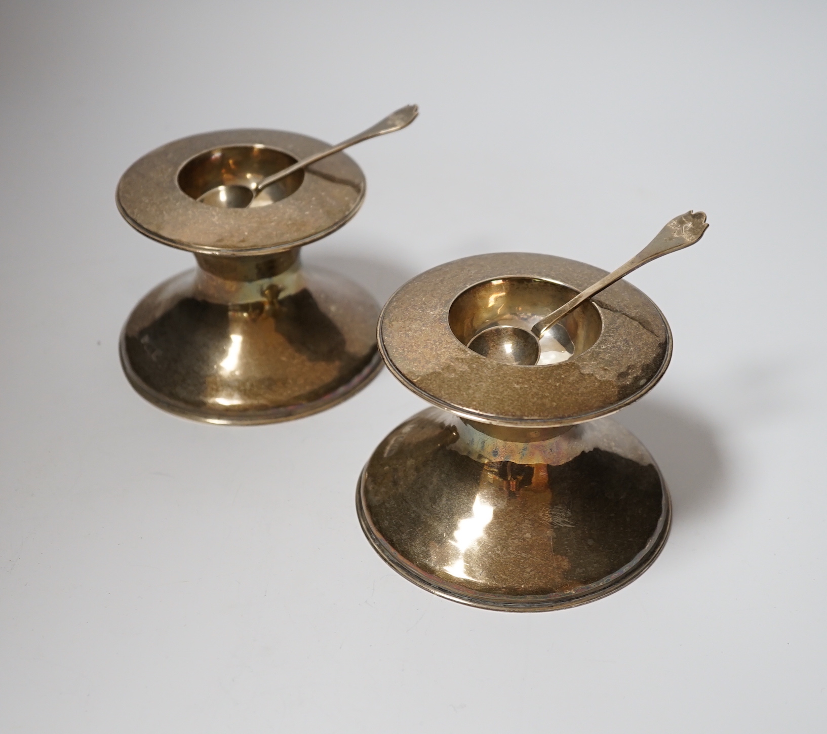 A pair of George V Britannia standard silver salts, of waisted form, with two matching spoons, Lambert & Co, London, 1910, height 79mm, 22oz.